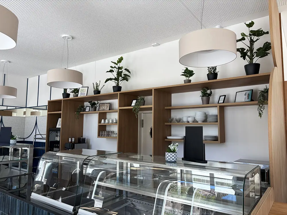 Marienkirchblick-Bistro: Theke mit Regalen, Lampen und Pflanzen. Bistro-Ambiente, moderne Einrichtung.