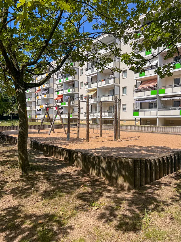 Spielplatz vor Wohnhaus am Juri-Gagarin-Ring. Sandkasten und Spielgeräte im Vordergrund. Mehrstöckiges Gebäude im Hintergrund.