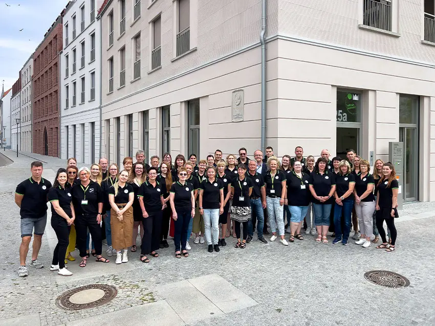 WOWI-FFO-Team: Gruppenfoto des Teams vor Gebäude. Alle tragen schwarze Poloshirts.