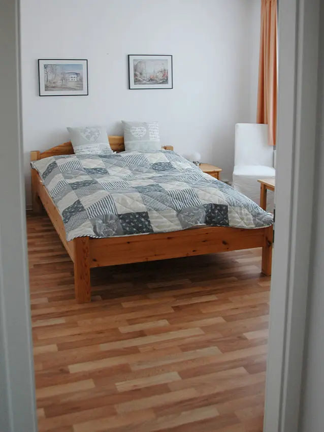 WOWI-FFO-Frankfurt-Oder-Moebliertes-Wohnen-1 Möbliertes Wohnen: Bett mit Patchwork-Decke, Kissen und Bildern an der Wand.