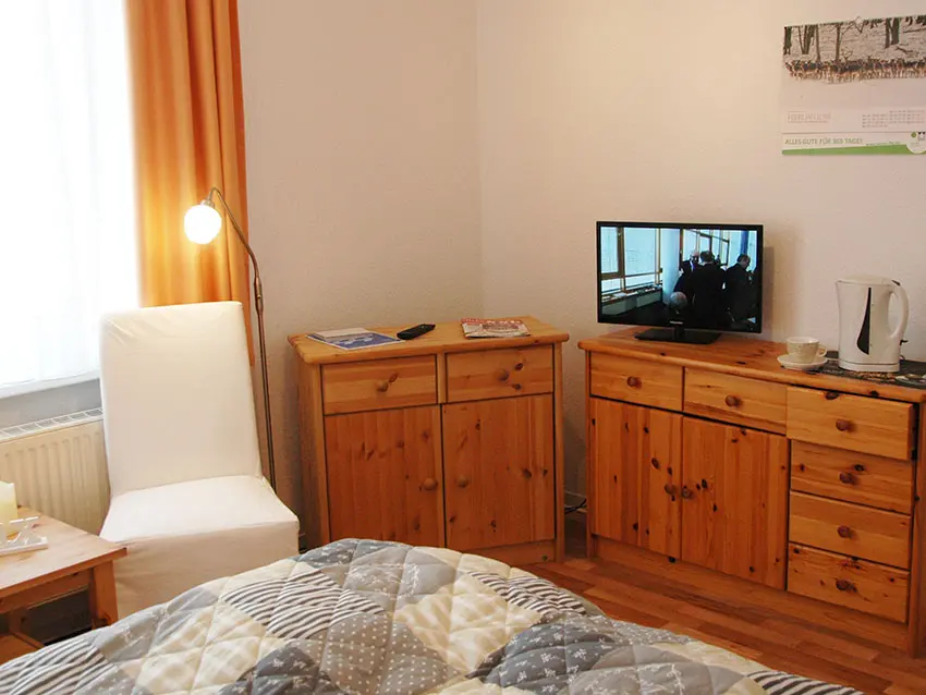 WOWI-FFO-Frankfurt-Oder-Moebliertes-Wohnen-13 Möbliertes Wohnen: Zimmer mit TV, Bett, Stuhl und Holzmöbeln.
