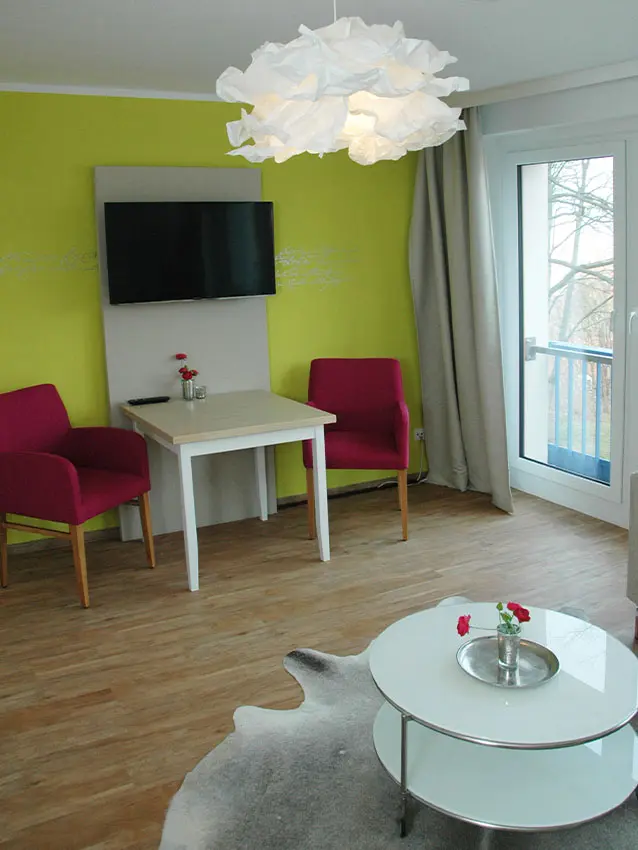 WOWI-FFO-Frankfurt-Oder-Moebliertes-Wohnen-16 Möbliertes Wohnen: Zimmer mit Tisch, Stühlen, TV und Lampe.