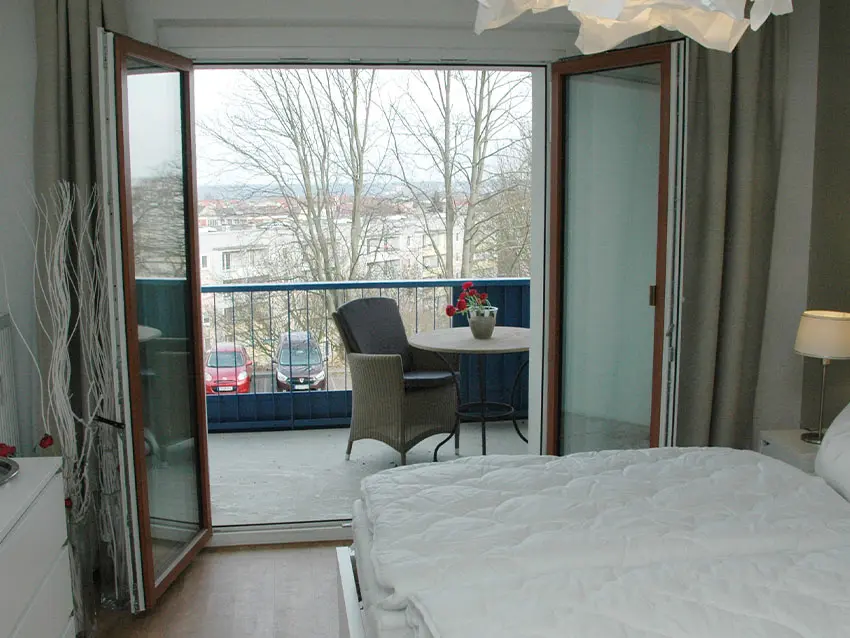 WOWI-FFO-Frankfurt-Oder-Moebliertes-Wohnen-5 Möbliertes Wohnen: Zimmer mit Bett und Balkon mit Tisch und Stuhl.
