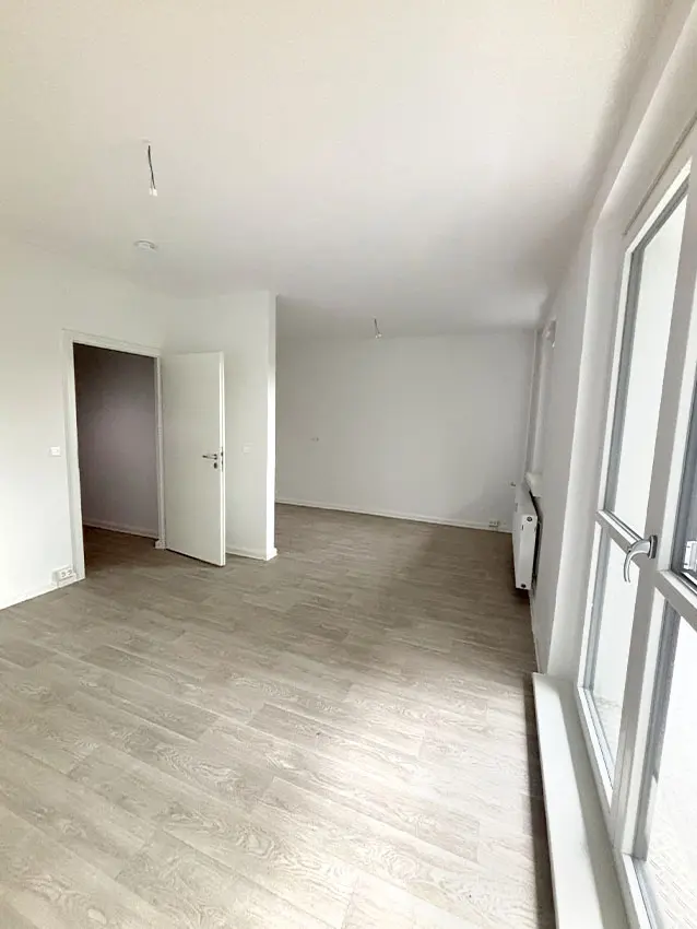 WOWI-FFO-Juri-Gagarin-Ring-16-Innen-2 WOWI-FFO Juri-Gagarin-Ring: Innenansicht einer hellen, leeren Wohnung mit Laminatboden und Fenster.