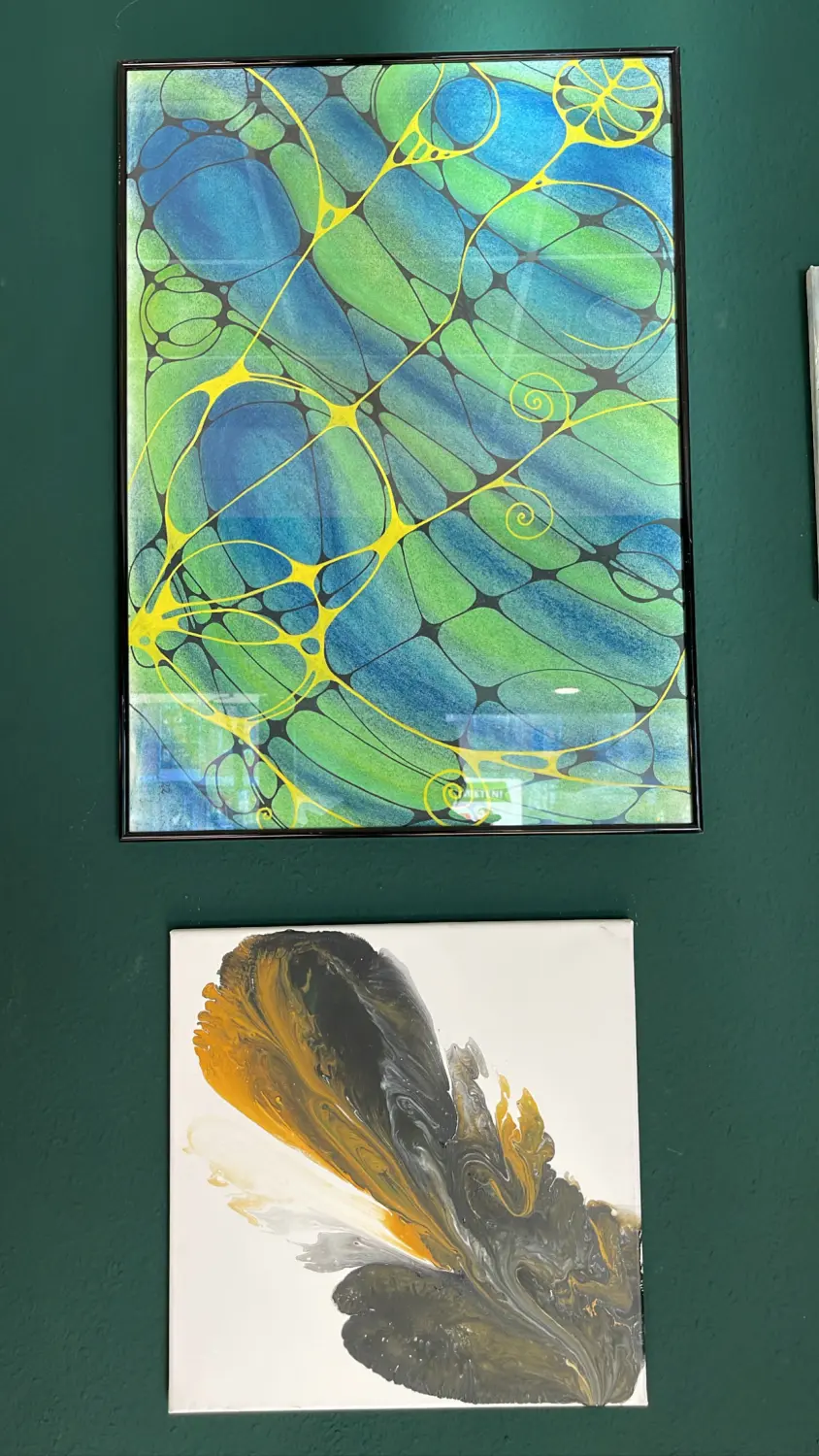 Wander-Atelier der Talente: Gerahmtes abstraktes Kunstwerk in Blau, Grün und Gelb. Ein weiteres Kunstwerk darunter.