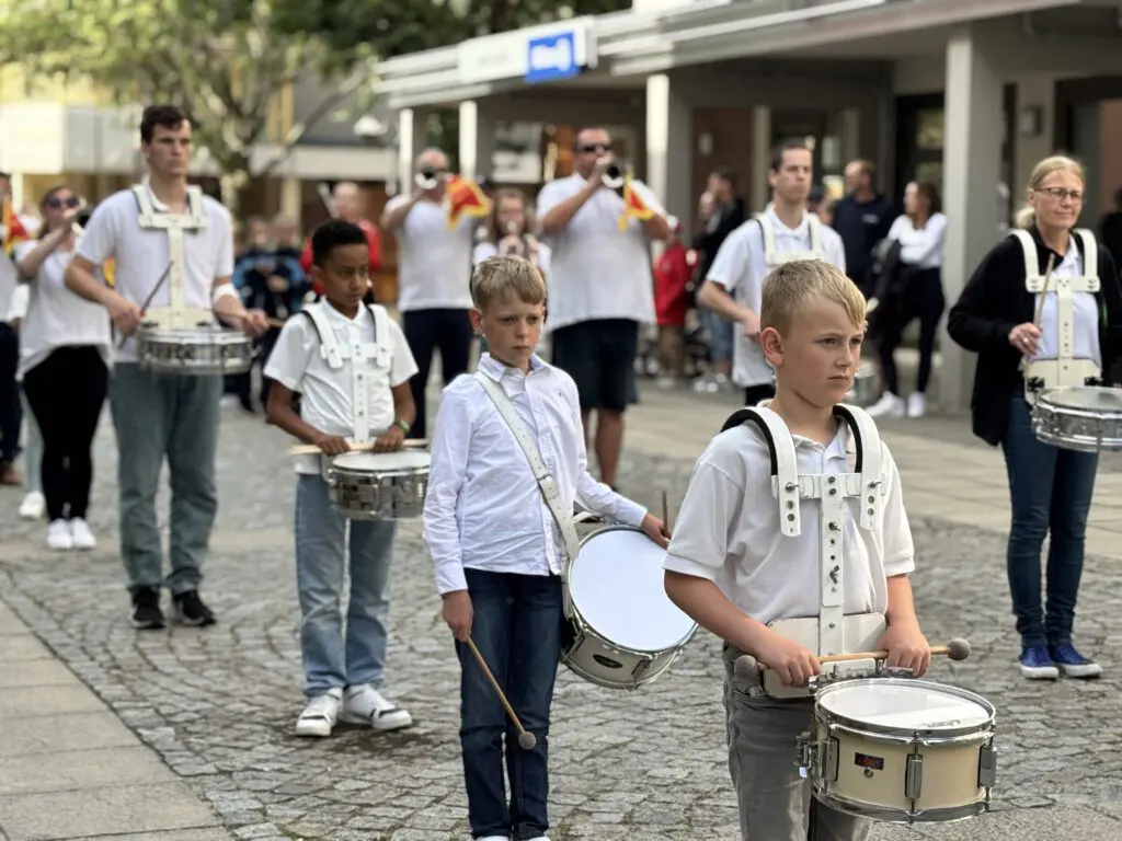 Junge Schlagzeuger tragen bei Treppenhausmusik 2027 ihre Trommeln mit Tragegestellen beim Marsch ueber das Kopfsteinpflaster