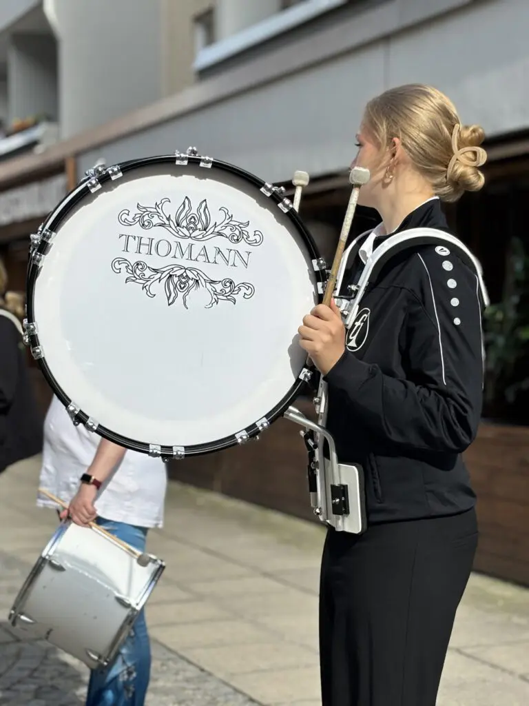 Eine Musikerin mit Thomann Basstrommel in schwarzer Sportjacke spielt bei Treppenhausmusik 2027 im Stehen auf der Strasse