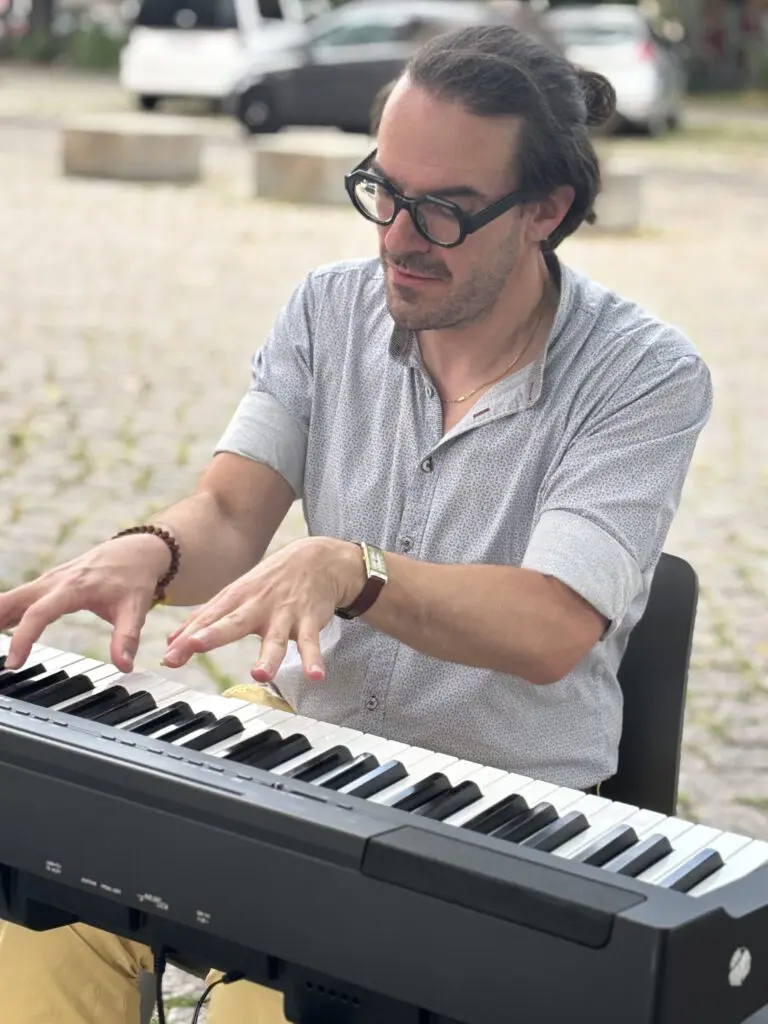 Ein Brillentraeger spielt bei Treppenhausmusik 2027 konzentriert auf einem Keyboard waehrend er auf einem Stuhl sitzt