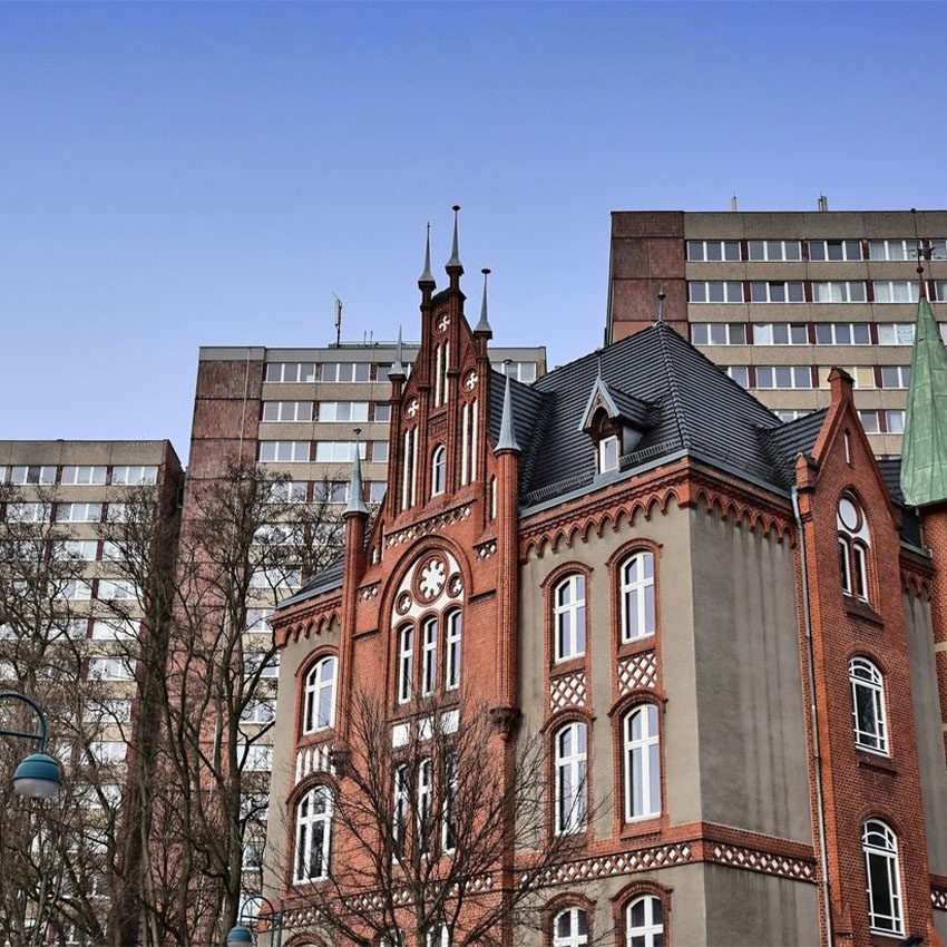 Architektur: Backsteingebäude mit Türmchen vor Hochhäusern.