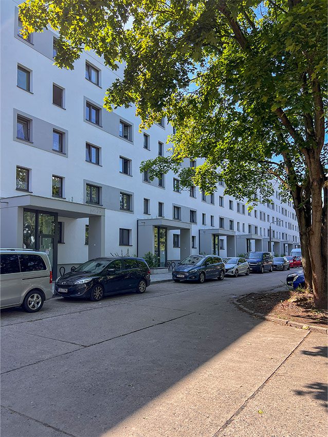 Mehrgeschossiges Wohngebäude am Juri-Gagarin-Ring mit geparkten Autos und Baum im Vordergrund.
