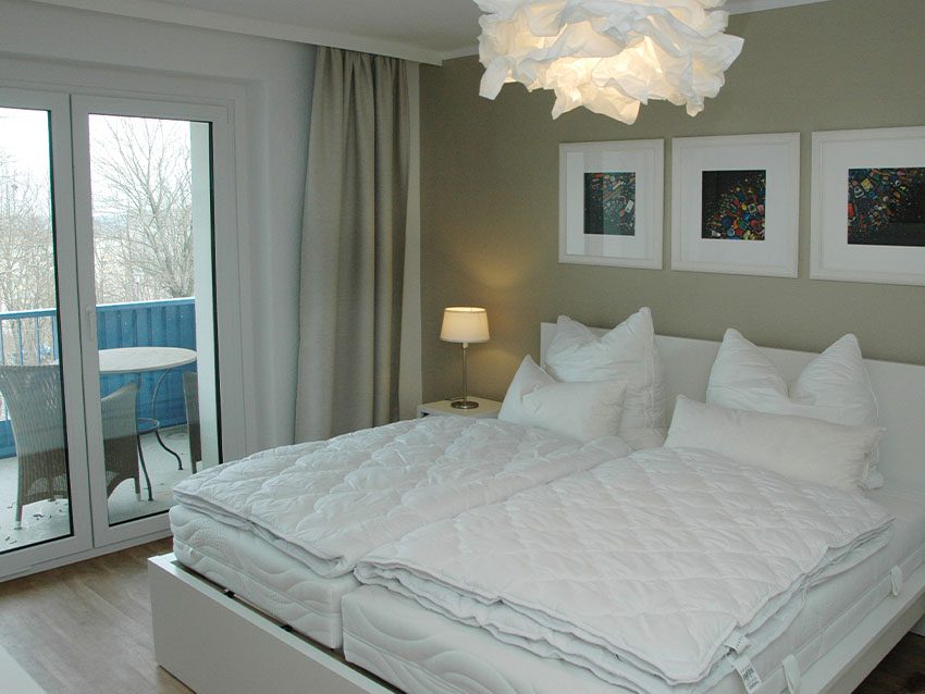 Helles, möbliertes Zimmer: Doppelbett, Balkon, Lampe. WOWI-Wohnen.